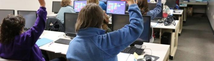 Imagen decorativa. Unos niños de secundaria levantan la mano en clase.